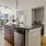 Kitchen with modern appliances and fixtures, adjacent to a living room with contemporary furniture and decor