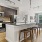 Kitchen with adjacent living room in a modern apartment, featuring sleek cabinetry and an open layout