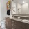 Well-lit bathroom with modern fixtures, including a large mirror, vanity, and stylish lighting