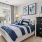 Well-lit modern bedroom with an upholstered bed, geometric-patterned pillows, a throw blanket, mirrored nightstands with lamps, and natural light coming through a large window