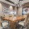 A modern conference room with a large wooden table, tan leather chairs, exposed brick walls, abstract artwork, and decorative lighting