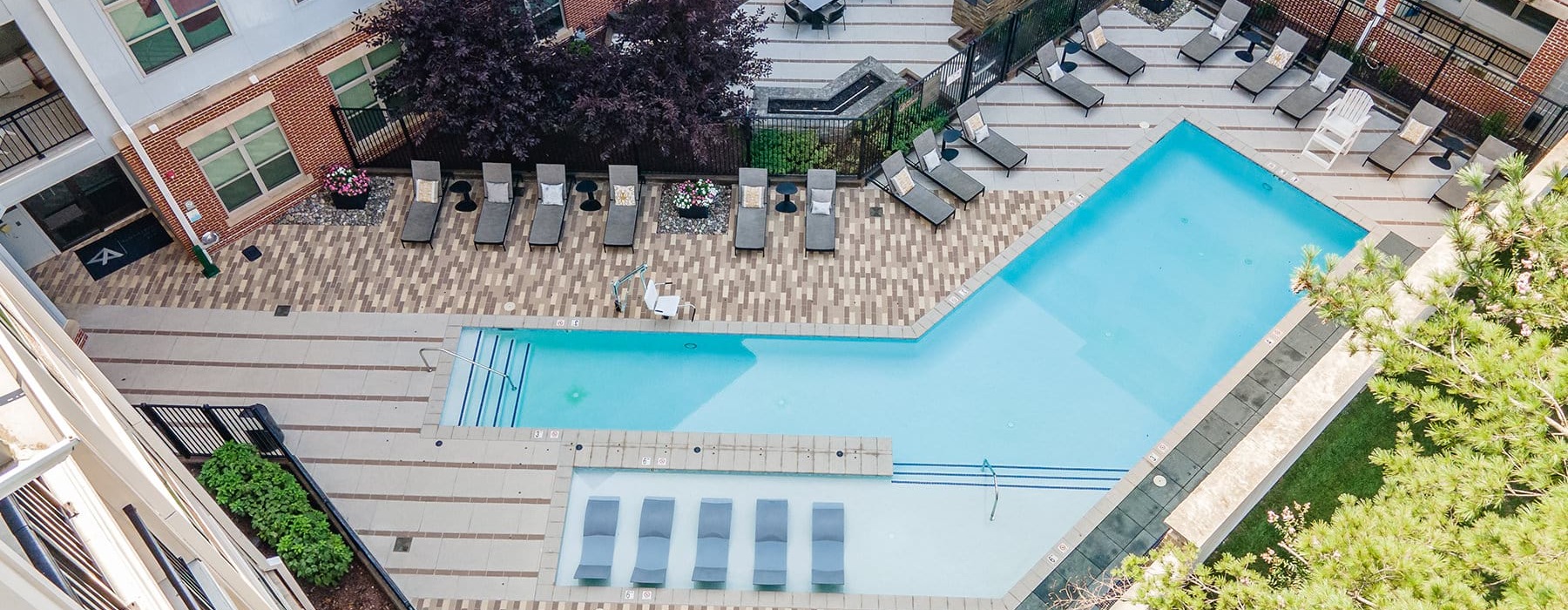 An aerial view of the outdoor pool area at Vista Wilde Lake, featuring lounge chairs, a patio with seating, and a rectangular swimming pool with in-water loungers